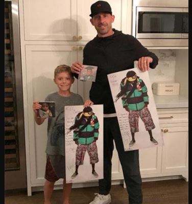 Carter Shanahan and his father Kyle Shanahan showing Lil Wayne's autographed poster